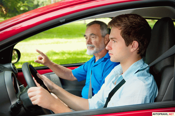 Подросток и инструктор сидящие за рулем автомобиля