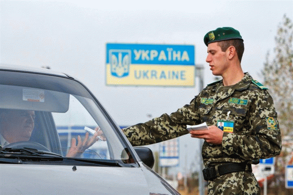 Пограничник проверяет документы у водителя на украинской таможне